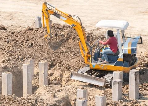 Close up of a mini digger operator excavating earth for a new building foun.. Stock Photos