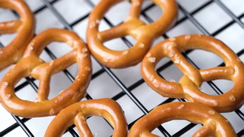 Close up mini salted pretzels on wire rack white background tracking shot Stock Footage