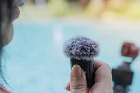 Close-up of a mini wireless microphone on female' hand while recording her .. Stock Photos