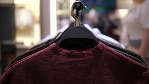 Close-up of minimalist dark red tees displayed in a bustling store, contrasting Stock Footage 316765935