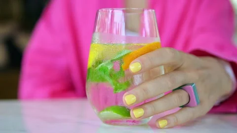A close-up of a misted clear glass on a cafe table. A woman's hand with a bright Stock Footage 217415272