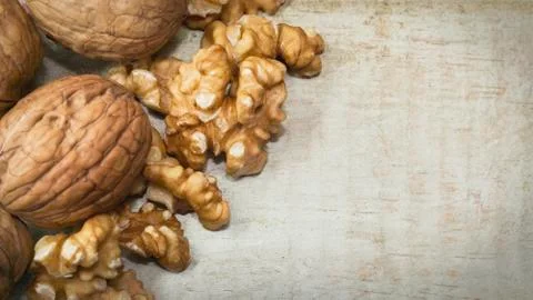 Close up of mix of walnut shells and walnuts kernels on light wooden surface 写真素材