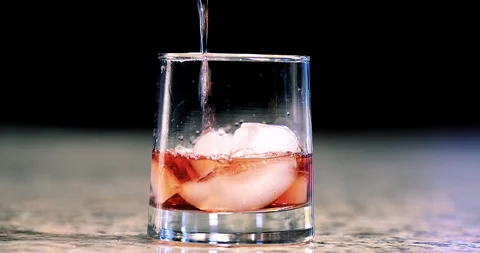 Close up of a mixed cocktail being poured into a glass &amp; garnishing with orange Stock Footage 104523236