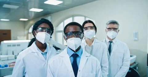 Close up of mixed-race different doctors in masks and goggles standing in clinic Stock Photos