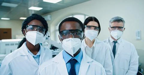 Close up of mixed-race different doctors in masks and goggles standing in clinic Stock Photos