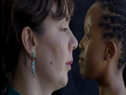 Close up on mixed race friends' faces against dark background 4K Stock Footage 78676173