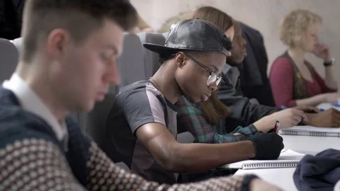 Close-up of mixed-race students taking notes in a lecture Stock Footage 74605821