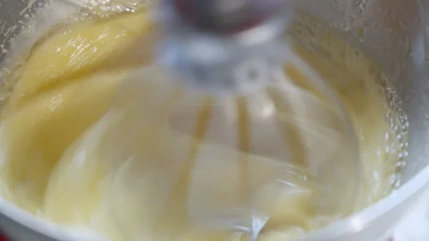 Close-up mixing egg and sugar in a metal bowl with electric kichen mixer. Stock Footage 275249736