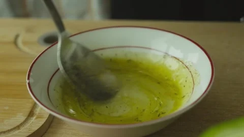 Close-up of mixing fresh salad dressing in a kitchen bowl. Homemade vinaigrette Stock Footage 340384976