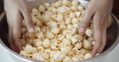 Close up mixing popcorn with their hands in the baking bowl, Slow Motion, 4K Stock Footage 108530278
