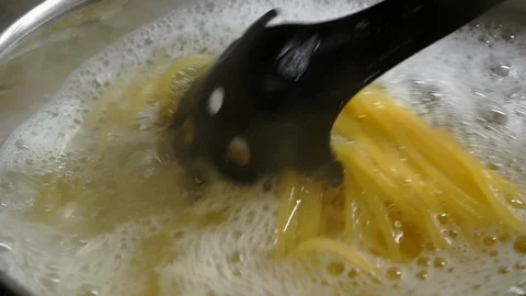 Close-up mixing spaghetti pasta in a pot of boiling water Stock Footage 102065279
