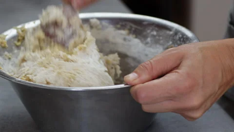 Close up of mixing white flour into dense yellow split pea dough in a metal.. Vídeo Stock 347078720