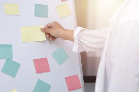 Close up mn hand taking  yellow sticky note on the whiteboard. Reminder plann Stock Photos