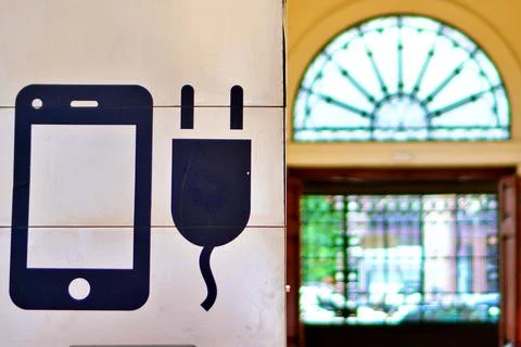 Close-up of mobile charging point symbol with train station background Stock Photos