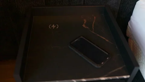 Close-up of a mobile phone screen up on a black luxury nightstand in bedroom. Co Stock Footage 341950636