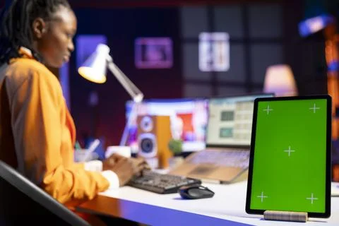 Close up of mockup electronic device next to remote employee using laptop Stock Photos
