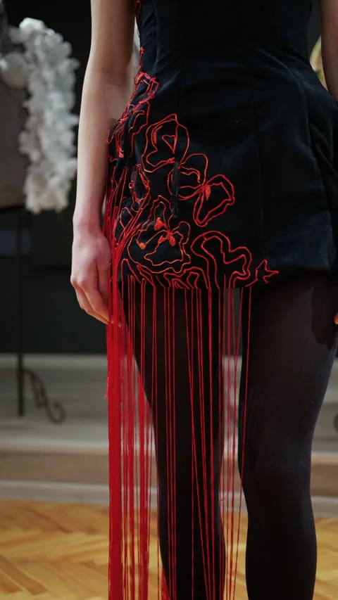 Close up of a model wearing a black outfit with red thread elements extending Stock Footage 335351908