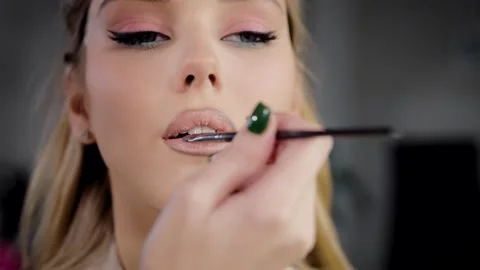 Close-up of the model's face, makeup artist applies lipstick to the lips of a Stock Footage 236300363