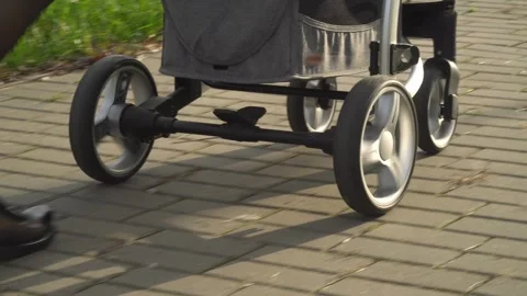 Close-up of a modern baby strollers wheels rolling smoothly on a paved path Stock Footage 321822792