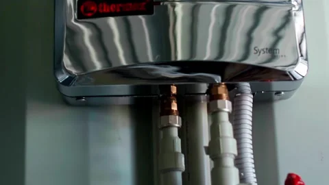 Close up of a modern chrome electric instant water heater on the wall Stock-Footage 332464434