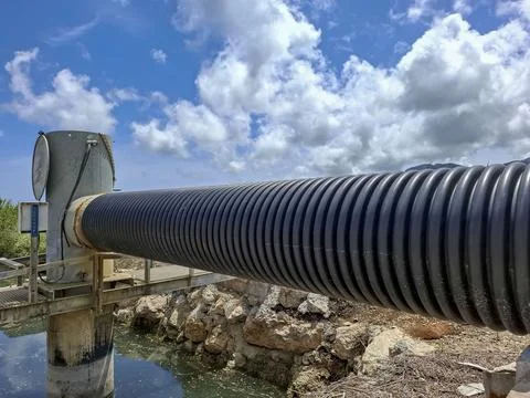 Close up of modern corrugated polyethylene pipe attached to concrete water .. Stock Photos