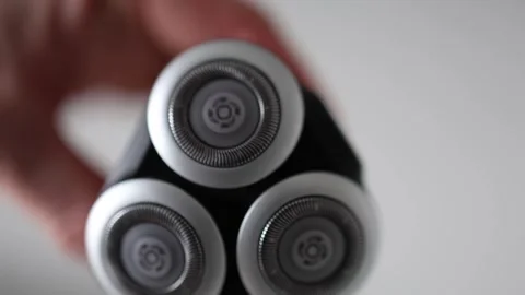 Close-up of a modern electric shaver with three rotating blades. The sleek silve Stock Footage 303908261