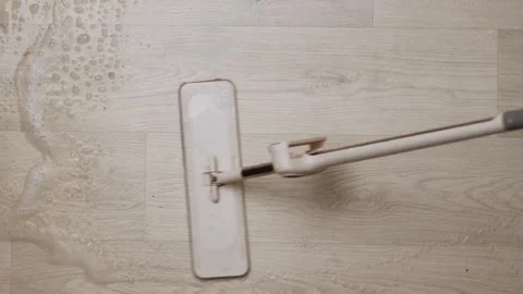 Close-up of a modern mop cleaning a light wood-look floor with suds Vidéo 339070259