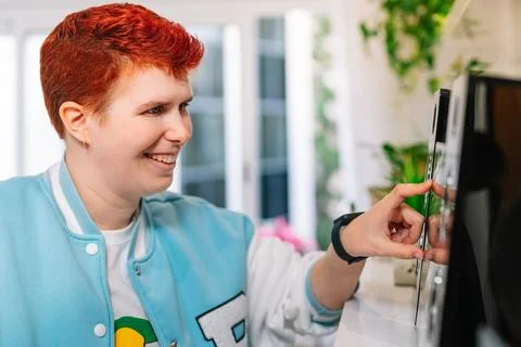 Close-up of a Modern, short-haired, red-haired, non-binary woman, turns on mini Stock Photos