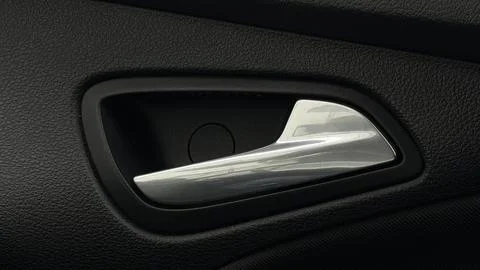 Close-up of a modern silver chrome interior door handle against black textured Stock Photos