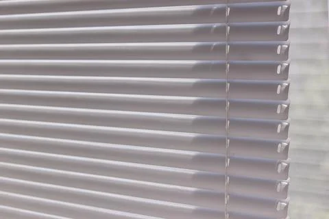 Close up of modern white window blinds filtering bright daylight Stock Photos