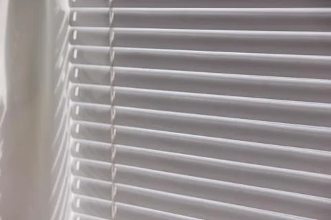Close up of modern white window blinds filtering bright daylight Stock Photos