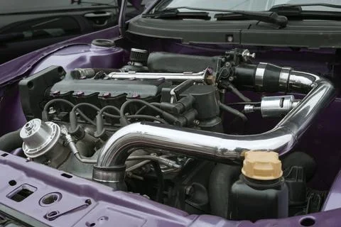 Close-up of a modified car engine bay with chrome piping, valve cover, and p Stock Photos
