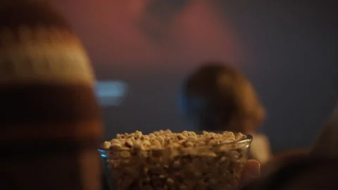 Close-up of mom and dads hands eating popcorn in front of home theater in fr Stock Footage 304275631