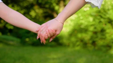 Close up mom and son hold hands, walk along the grass in a botanical garden Video stock 134230409