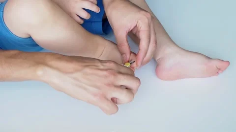 Close-up mom cuts off the baby's nails on the leg on white background Video stock 249461647