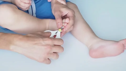 Close-up mom cuts off the baby's nails on the leg on white background Stock Footage 249526975