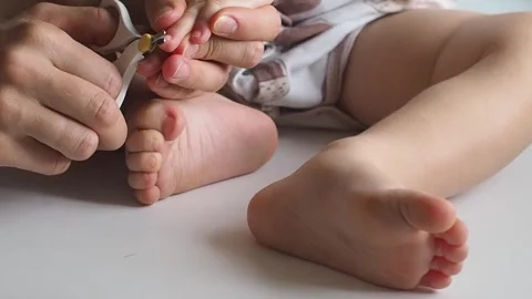 Close-up mom cuts off the baby's nails on the leg on white background Stock Footage 250116805