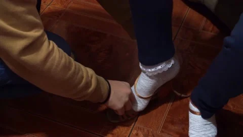 Close-up of a mom helping her little daughter to put on shoes with heels in 4K 動画素材 155308909