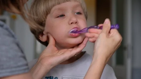 Close-up mom helps to clean the teeth to her little son in the morning. Mother Stock Footage 111717379