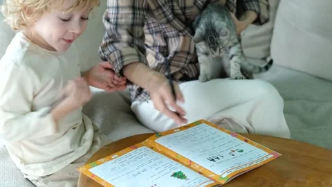 Close-up mom helps her son do his schoolwork at home 스톡 동영상 296446429