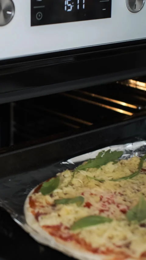 Close-up of mom inserts pizza into oven 動画素材 283581674