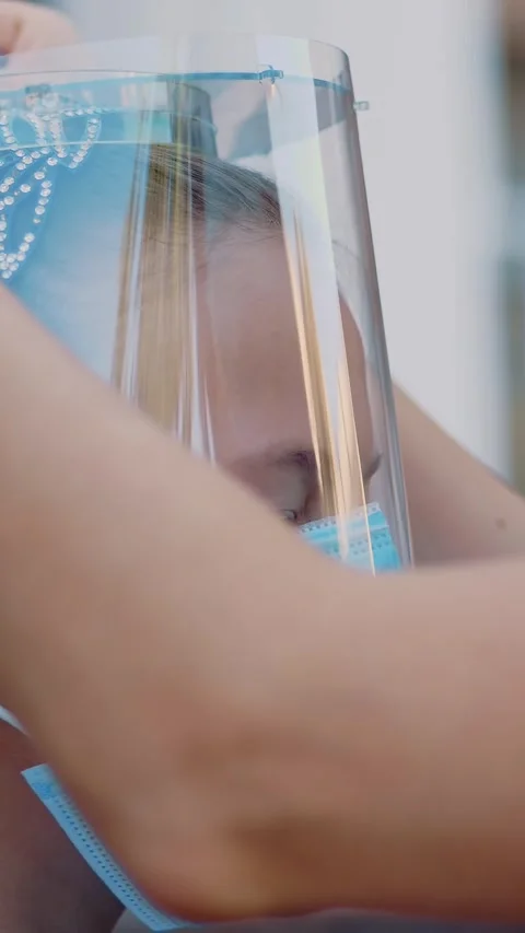 Close-up, mom puts protective face shield on her daughter schoolgirl, on school Stock Footage 318249085
