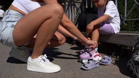 Close-up Mom putting on inline skates rollers knee protection to daughter child Stock Footage 237545954