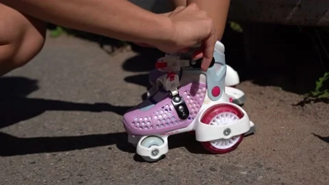 Close-up Mom putting on inline skates rollers to daughter child in public park Stock Footage 237545970