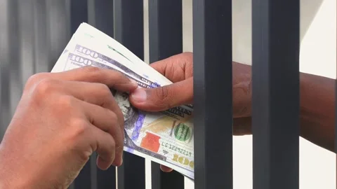 Close-up of money exchange through prison bars, symbolizing corruption Vídeos de archivo 335335864