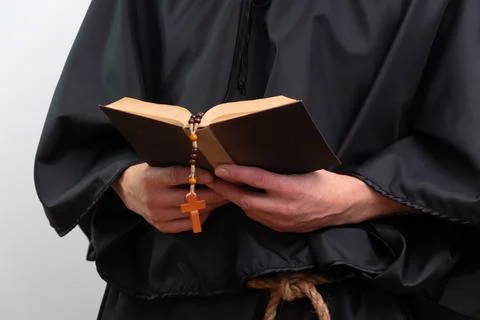 Close up of monk hands holding book and rosary isolated. Photos