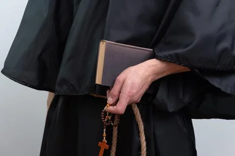 Close up of monk hands holding book and rosary isolated. Fotos de archivo