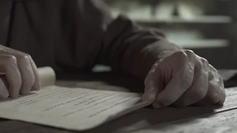 Close up of monk hands unrolling a parchment scroll on a wooden desk Stock Footage 338991463