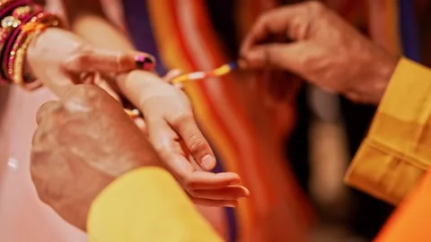 Close-up of a monk tying a sacred thread on a young teenage girl wrist at r.. 스톡 동영상 313258728