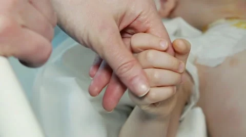 Close up of mother and sick child holding hands in a hospital bed Stock Footage